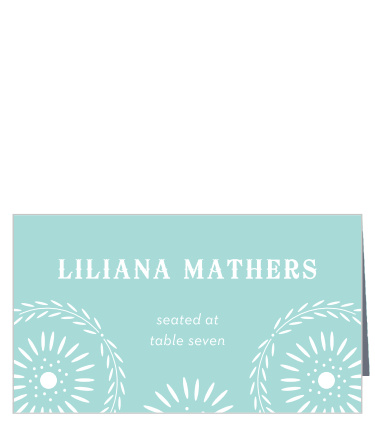 Our Papel Confetti Place Cards feature a daisy-esque papel picado design that frames your guests' names and table number atop a pastel, glass blue backdrop.